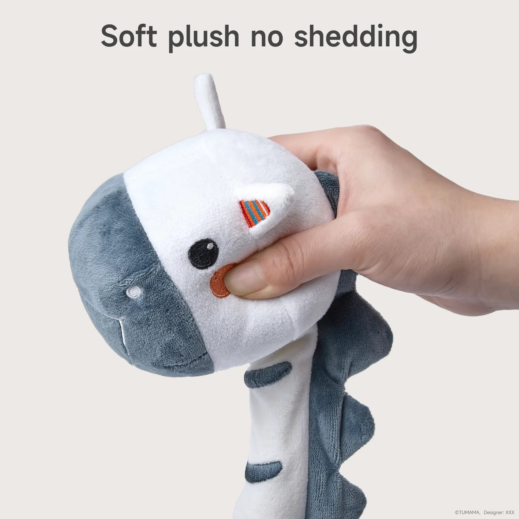 A close-up of a hand squeezing the zebra plush toy, showcasing its soft, non-shedding material and durable construction. The fabric looks gentle and smooth, perfect for babies and toddlers.