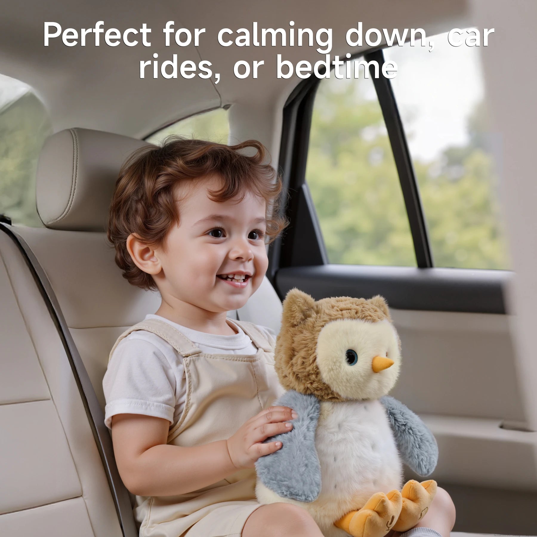 A smiling toddler sitting in the back seat of a car, holding a soft, interactive owl plush toy with brown, white, and gray fur. The text above reads: 'Perfect for calming down, car rides, or bedtime,' emphasizing the toy's soothing and comforting qualities.