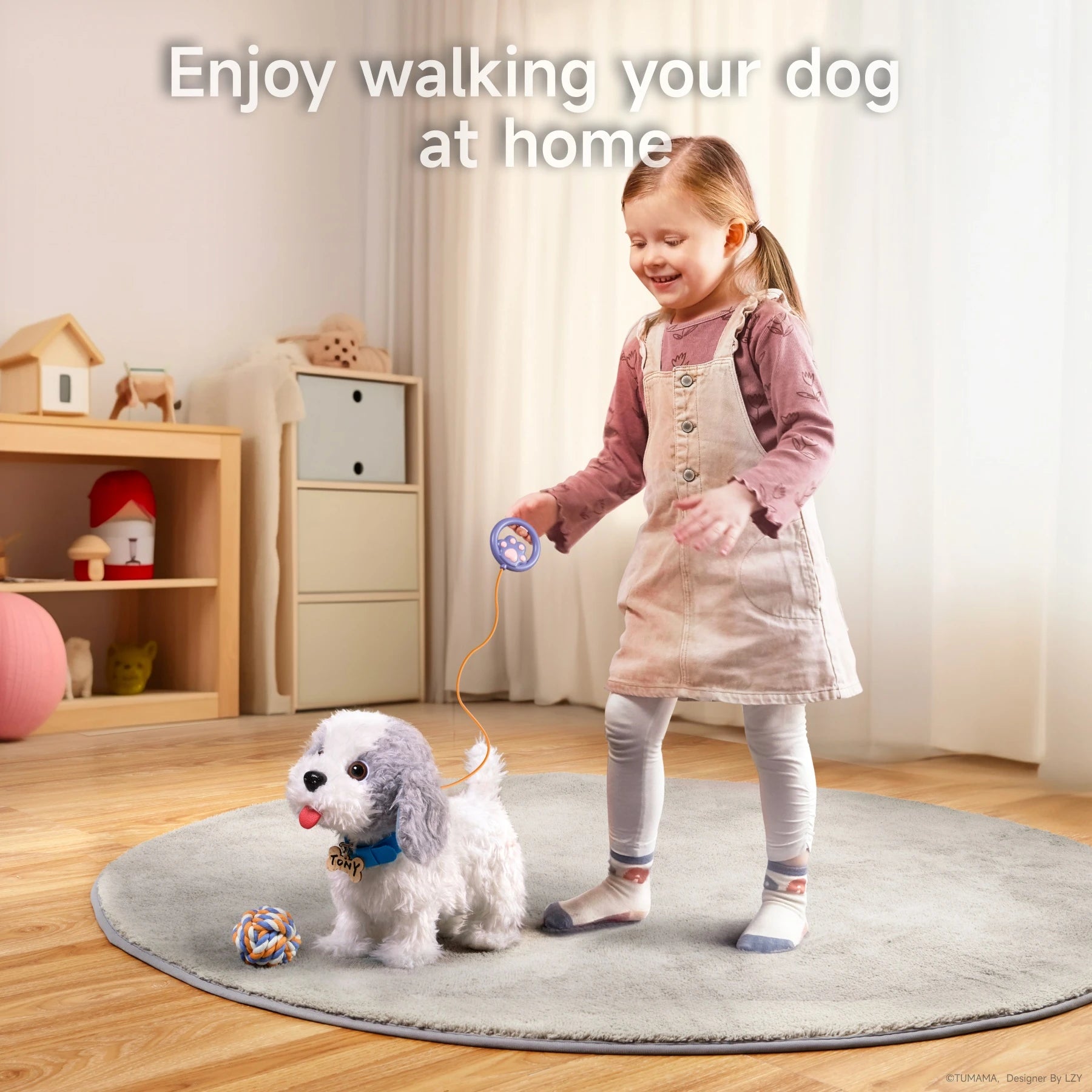 A young child walking a gray-and-white plush puppy toy using a leash remote. The puppy is on a round rug with a colorful rope ball nearby, in a cozy playroom setting. The child is smiling as they enjoy interactive indoor play with their toy dog.