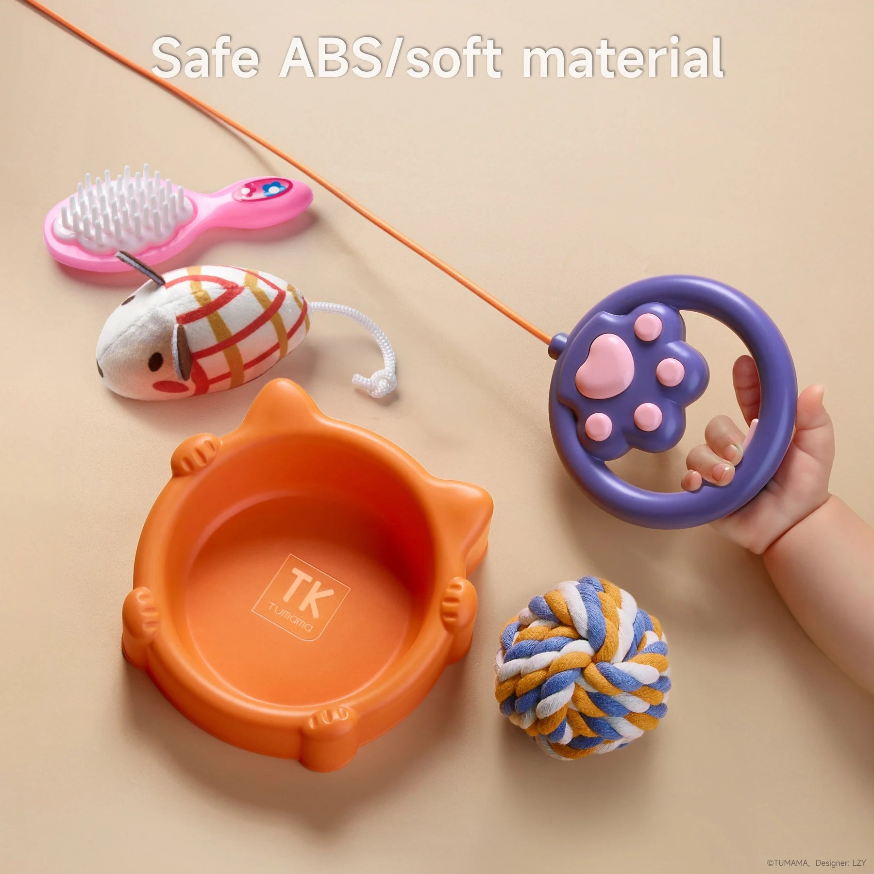 Close-up of toy cat accessories: an orange food bowl, plaid toy mouse, pink grooming brush, rope ball, and a purple paw-shaped leash remote held by a child. All items are made from safe, durable, and soft materials for children.